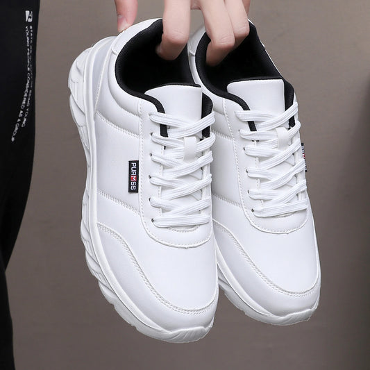 White sneakers with black accents held by a person against a neutral background